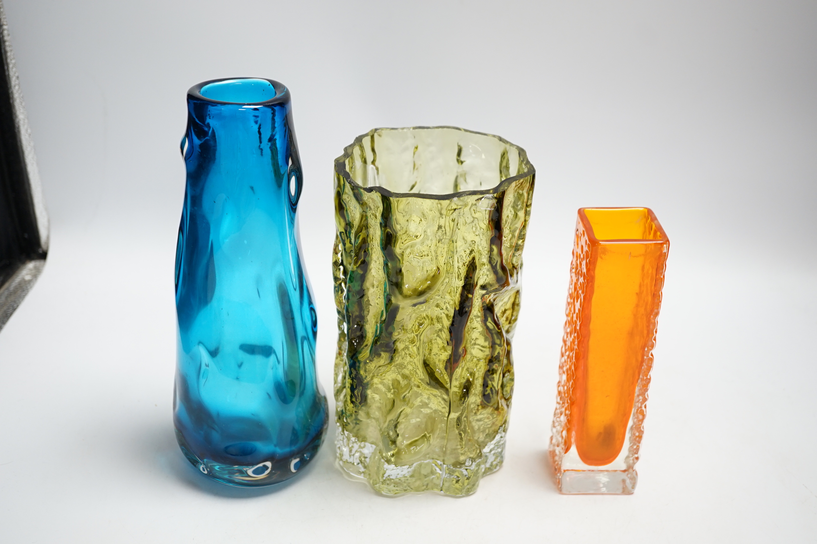 Three Whitefriars glass vases - a ‘Knobbly’ vase in kingfisher blue, a ‘Nailhead’ vase in tangerine and a ‘Bark’ vase in sage (cut down)